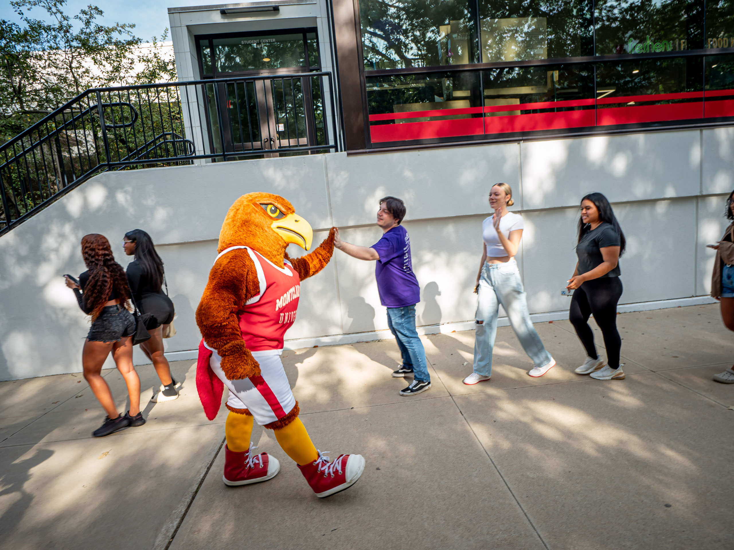 The mascot Rocky high-fives students as they walk past him.