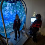 A student conducts testing on another student who is harnessed into the Bertec balance system.