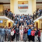 A large group of professionals pose for a photo on a staircase.