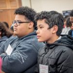 Seated male students listen during a conference.