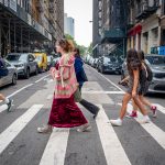 Students walk across a street in New York City.