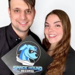 Corey Morgart and Therese Sheridan hold a sign that says Space Hound Records with a logo of a dog wearing a space helmet.