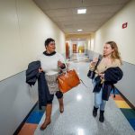 Two students walk down a hallway.