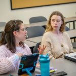 A student looks on as a classmate speaks in a classroom.
