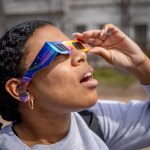 A student looks up wearing solar safety glasses.