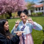 Student in traditional Korean dress waves.