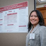  A student stands in front of her research poster.
