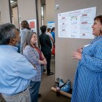 A student speaks as two people view her poster.