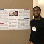  A man smiles in front of his research poster.