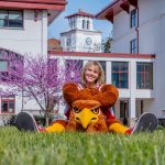  A costumed Vanessa Fingerlin sits on the grass behind a costumed bird head.