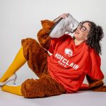  A costumed Eliza Andrus holds a sneaker as a phone while laughing.