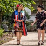 A graduate and her college-age daughter walk on campus.