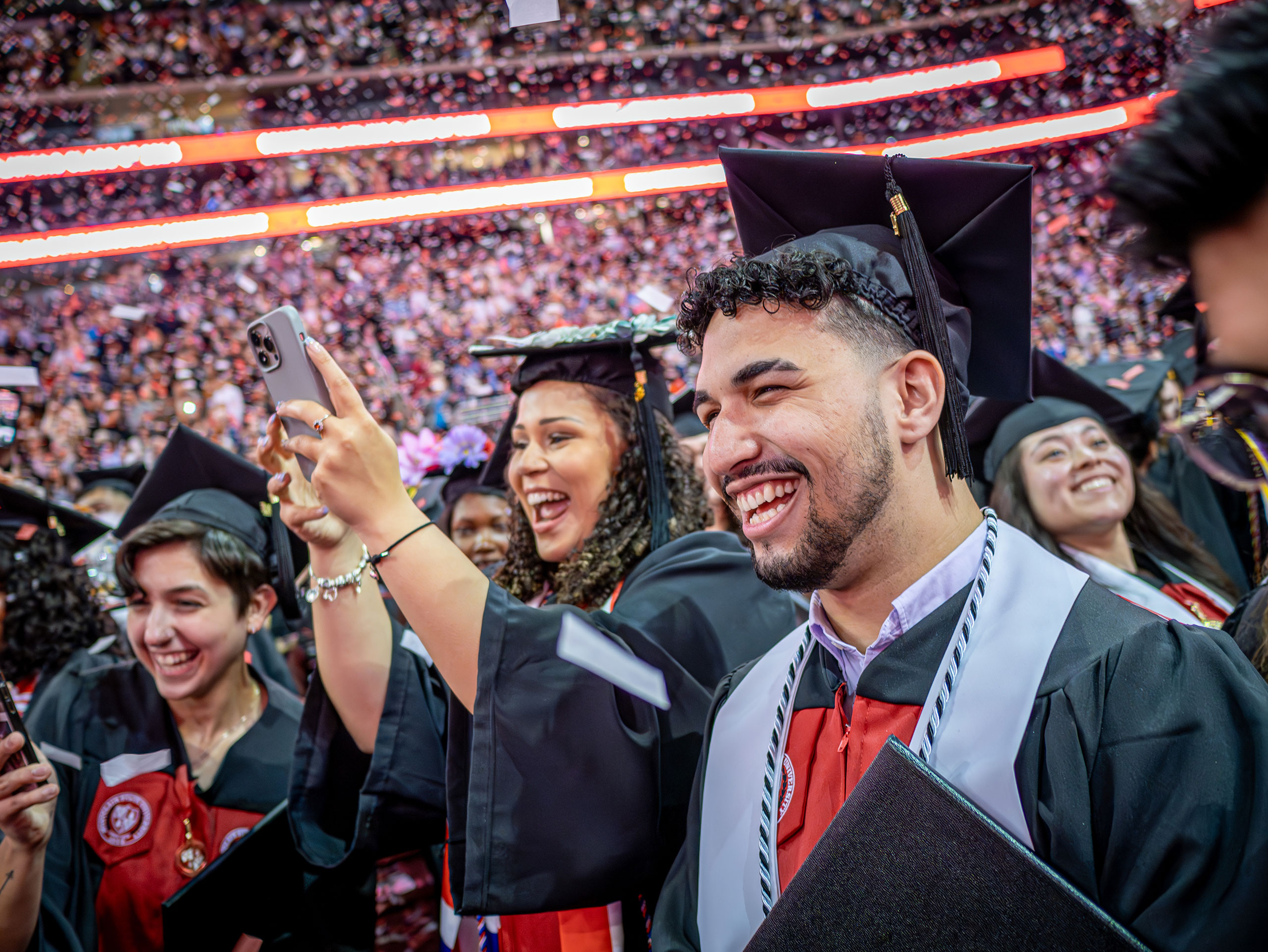 graduates smiling and taking photos as confetti falls