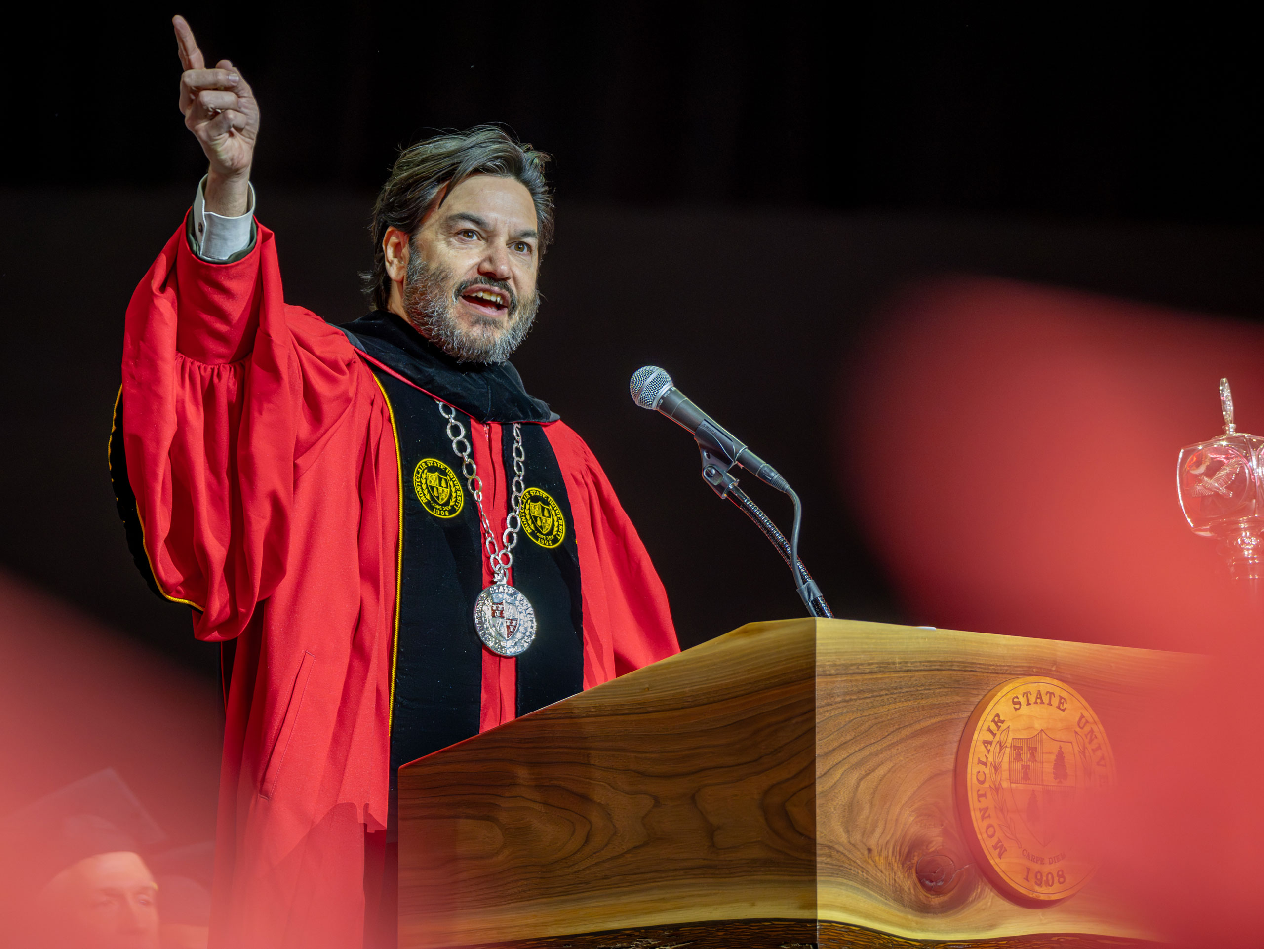 Montclair State University President Jonathan Koppell speaks at the podium during the Winter Commencement ceremony, addressing graduates.