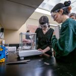 Katie Cicero looks on as Sarah Bowers lifts a test tube in the Chemistry lab.