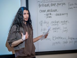 Godek presents in front of a white board in class about the qualities of the wine.