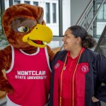 The Red Hawk mascot and a student smile at one another.