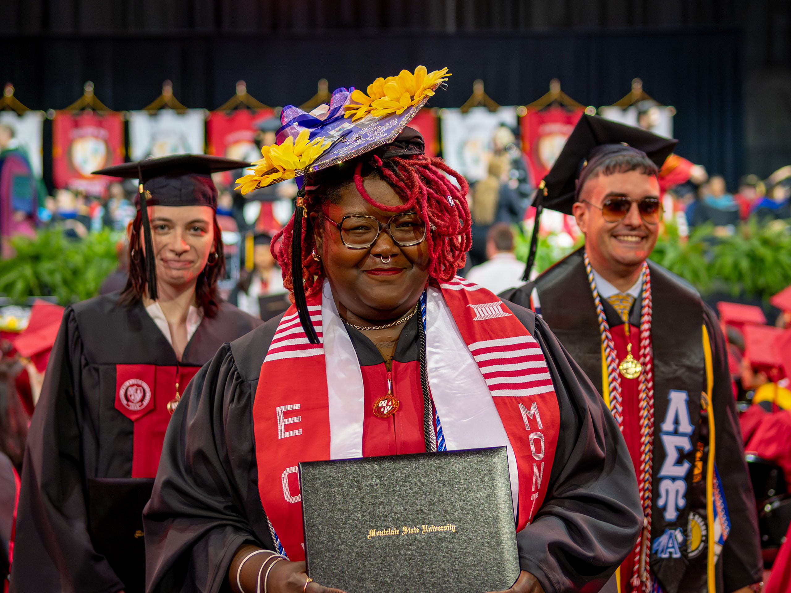 Khara Brown in her cap and gown, showing her diploma holder