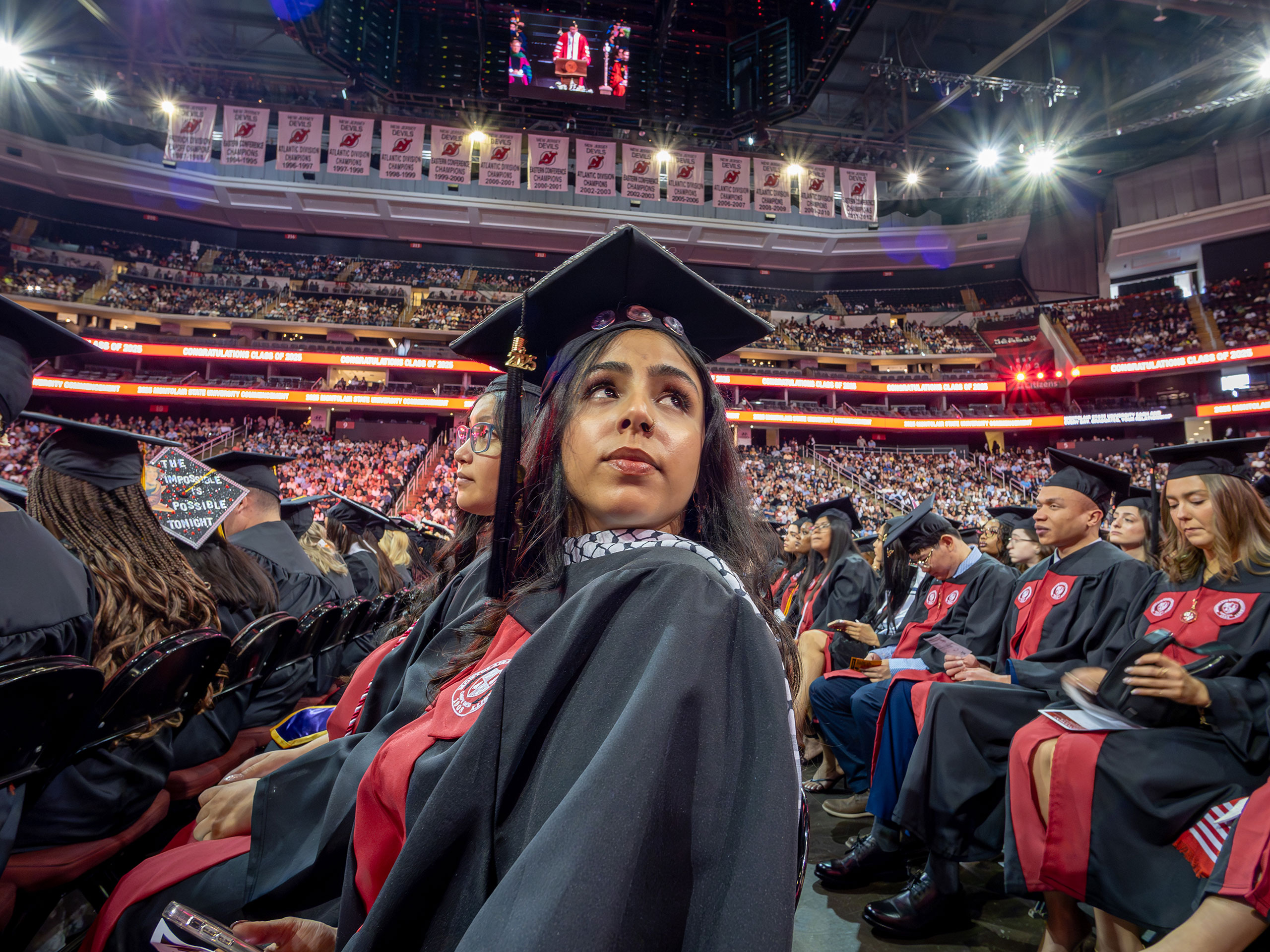 a graduate seated among peers looks toward the stands
