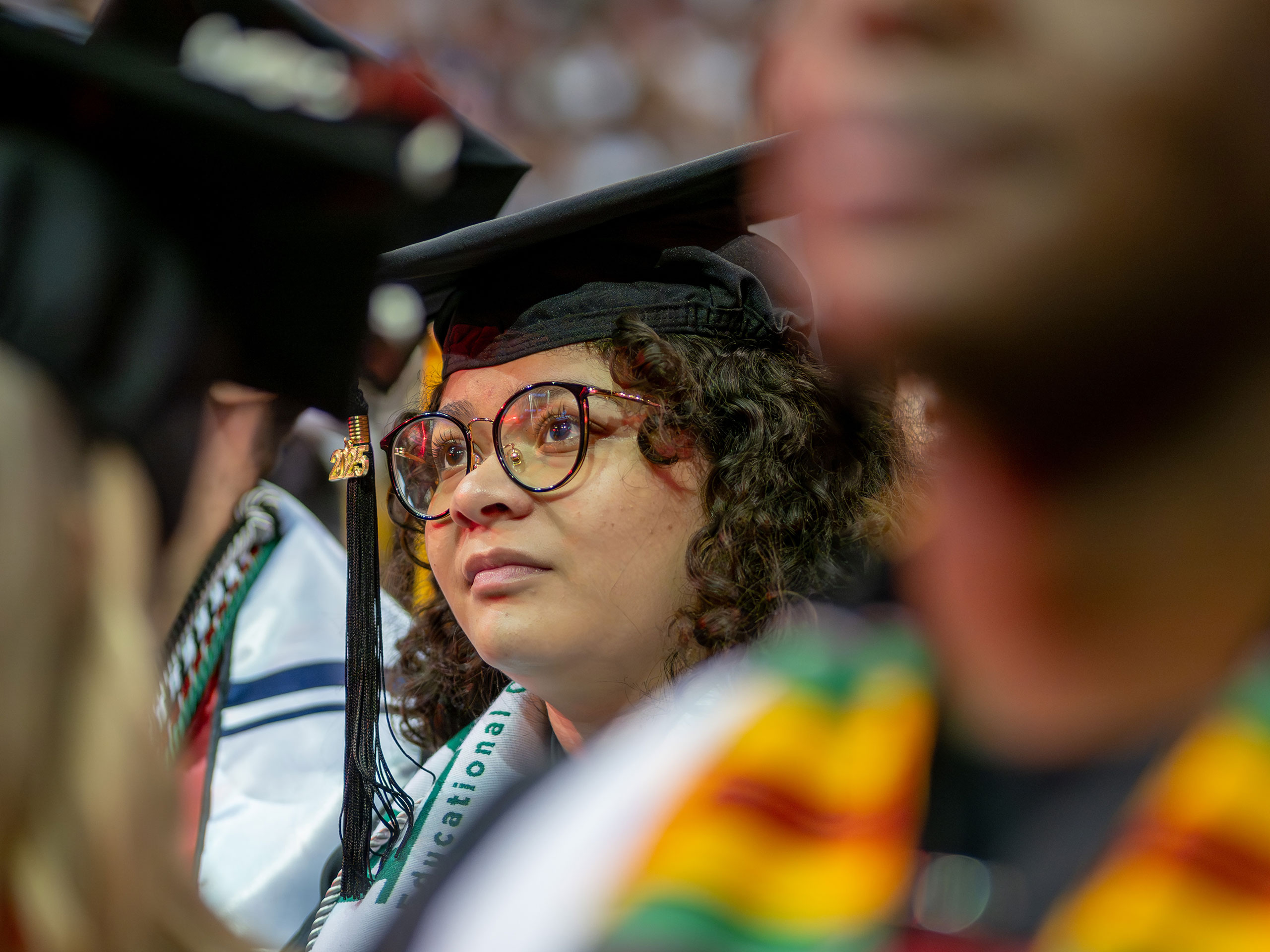 graduate in cap and gown looking toward the stage