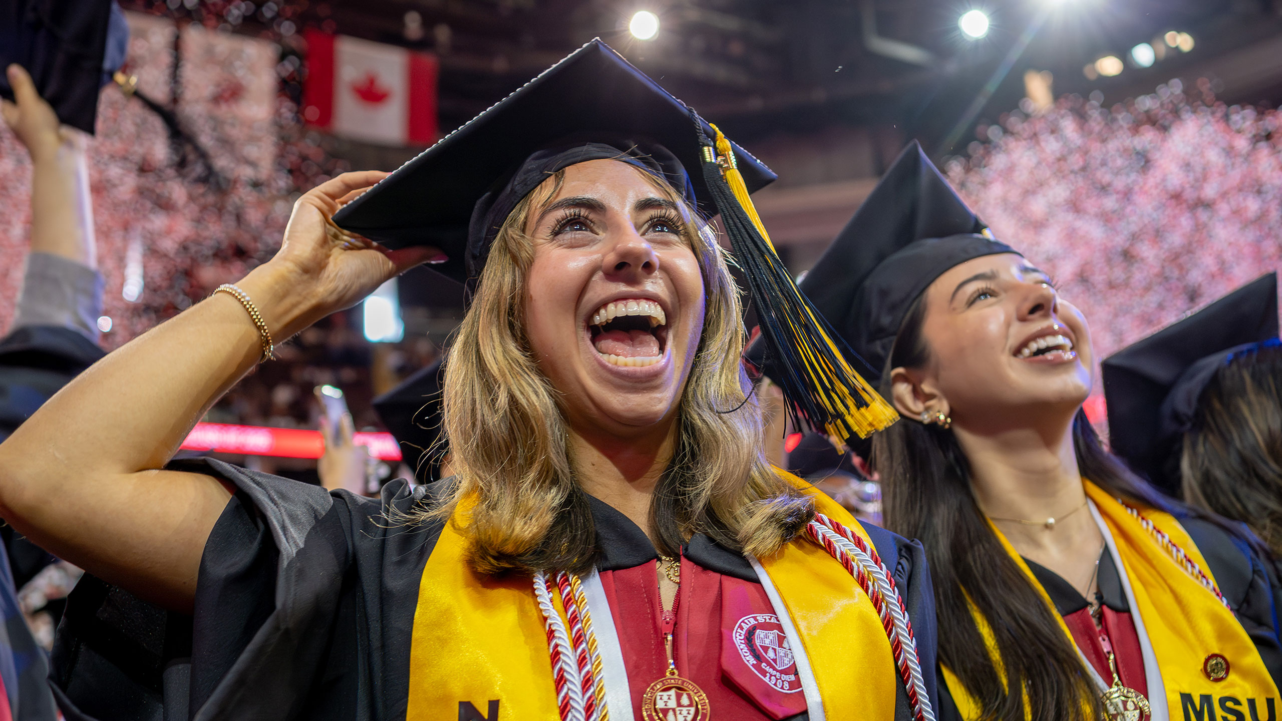 Two graduates smiling and looking toward the stage