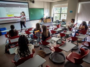 Associate Professor Lauren Covey stands at a whiteboard while teaching an Introduction to Cognitive Science class.