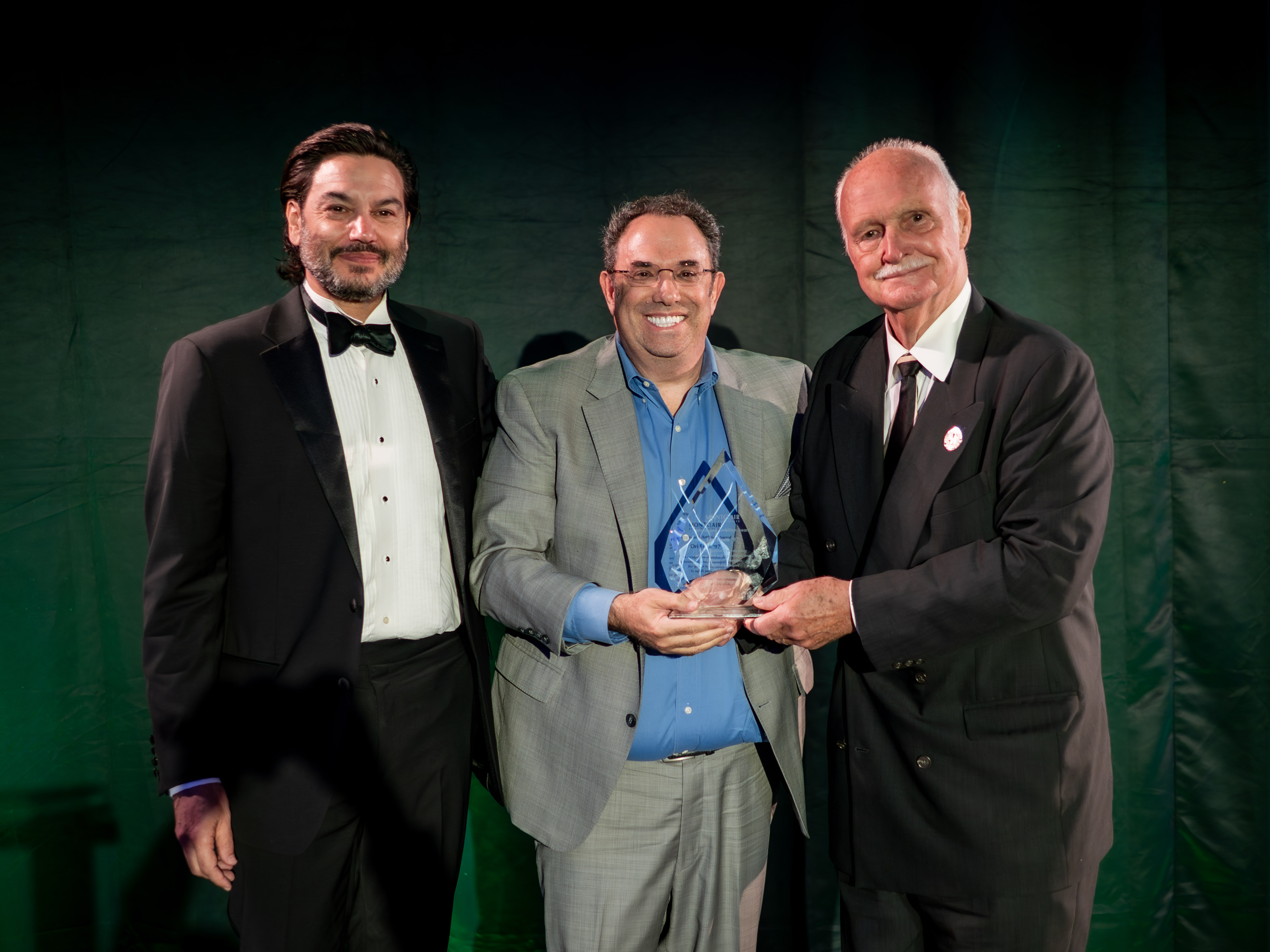 Three men posing with an award