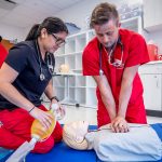 Nursing students performing CPR on medical manikin in simulation lab.