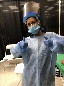 RN to BSN student in protective gear giving a thumbs up at vaccination site.