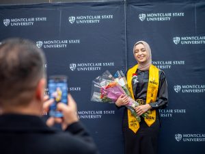 Nursing student holding a bouquet of flowers and posing for a photo at the Pinning Ceremony.