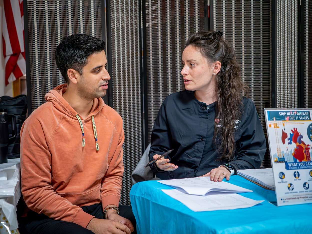 School of Nursing alumni sitting with health screening participant.