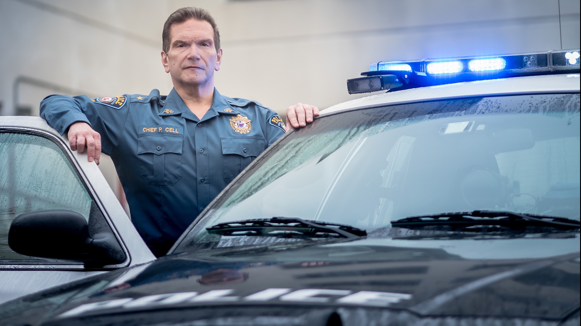 Police Chief Paul Cell in uniform, standing at a patrol car.