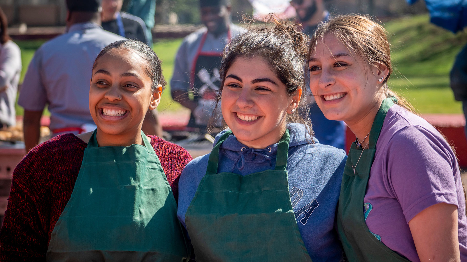 Smiling students with green aprons