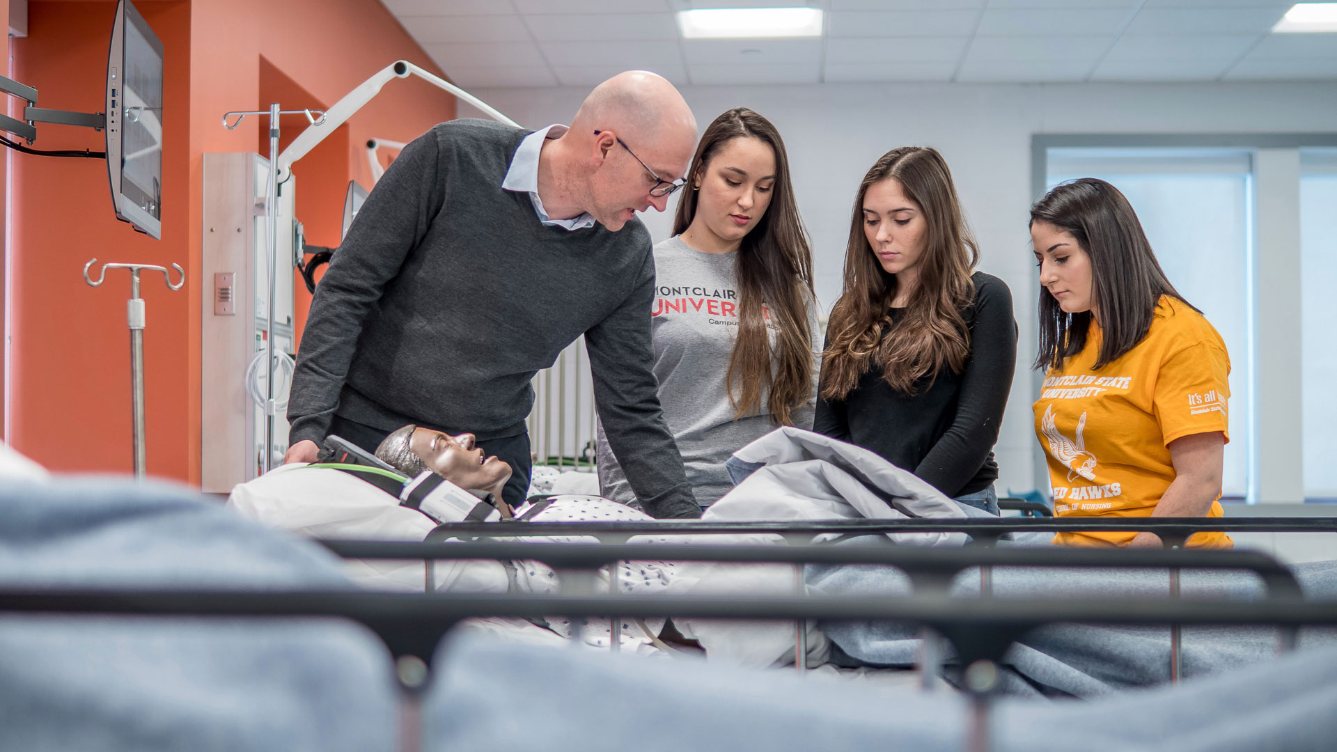 Nursing professor and students with practice dummy