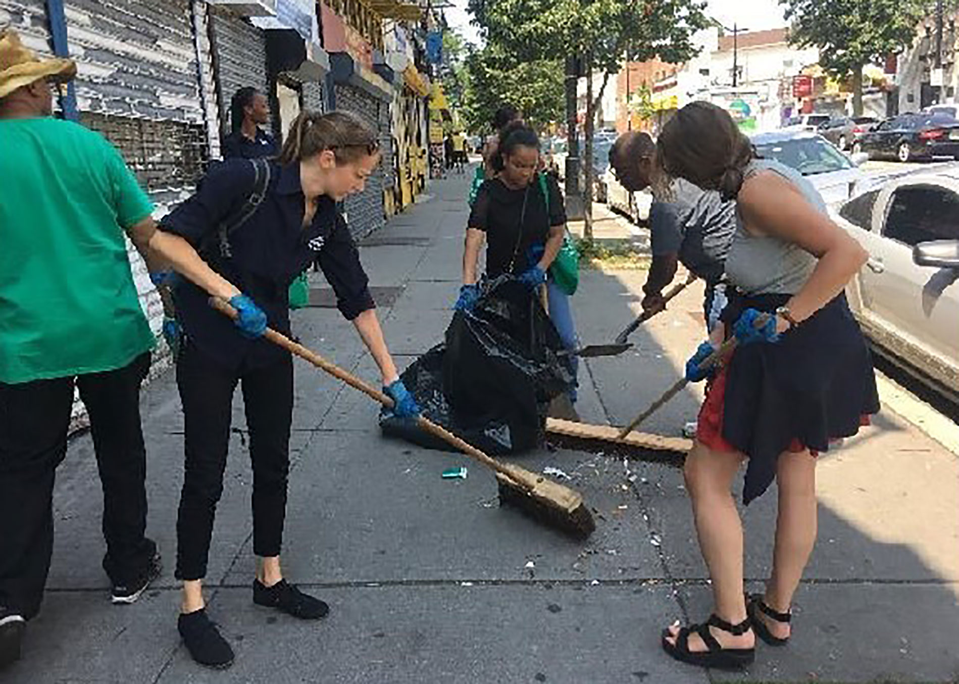 green team volunteer sidewalk sweeping