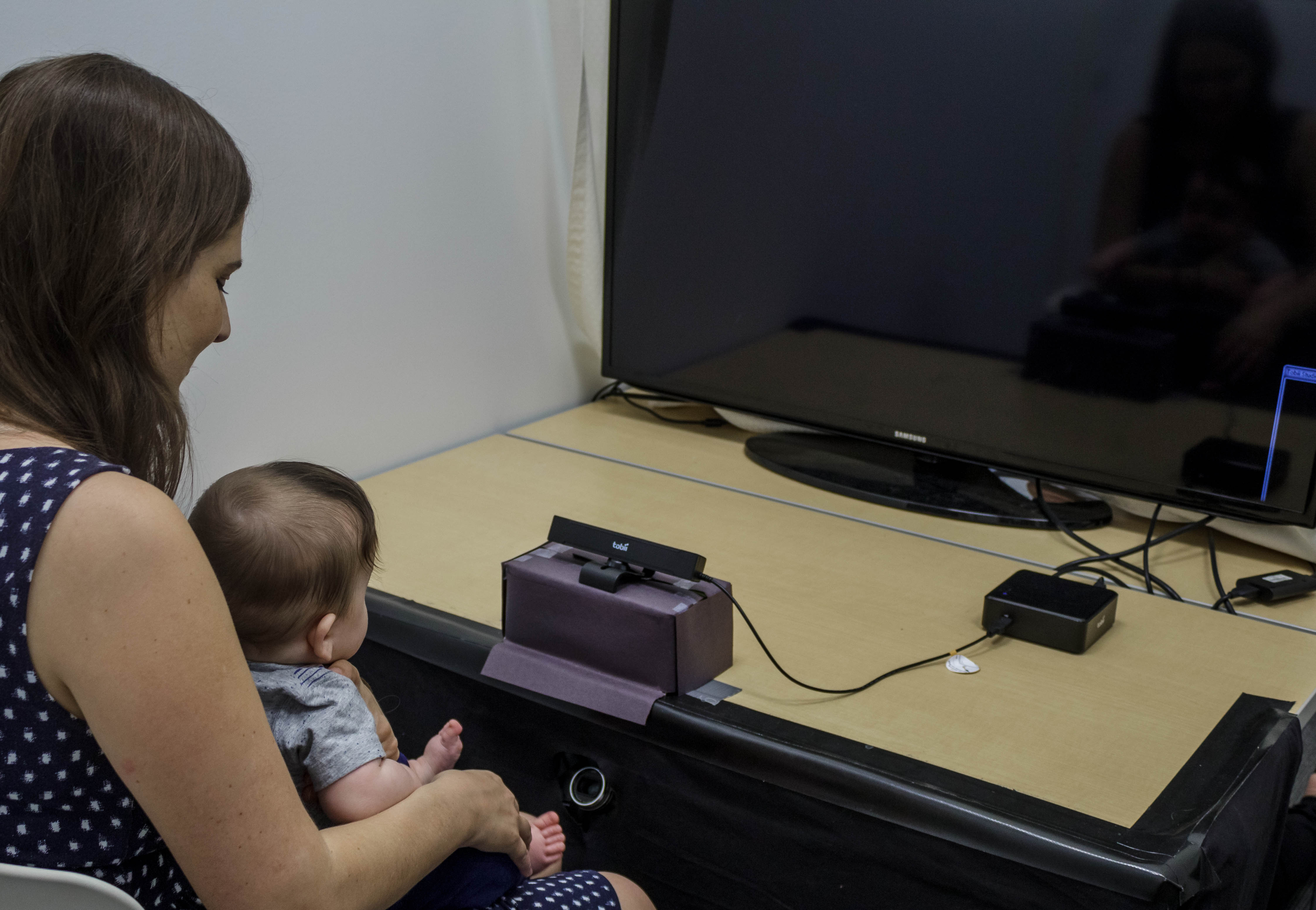 a women and a baby looking at a tv screen.
