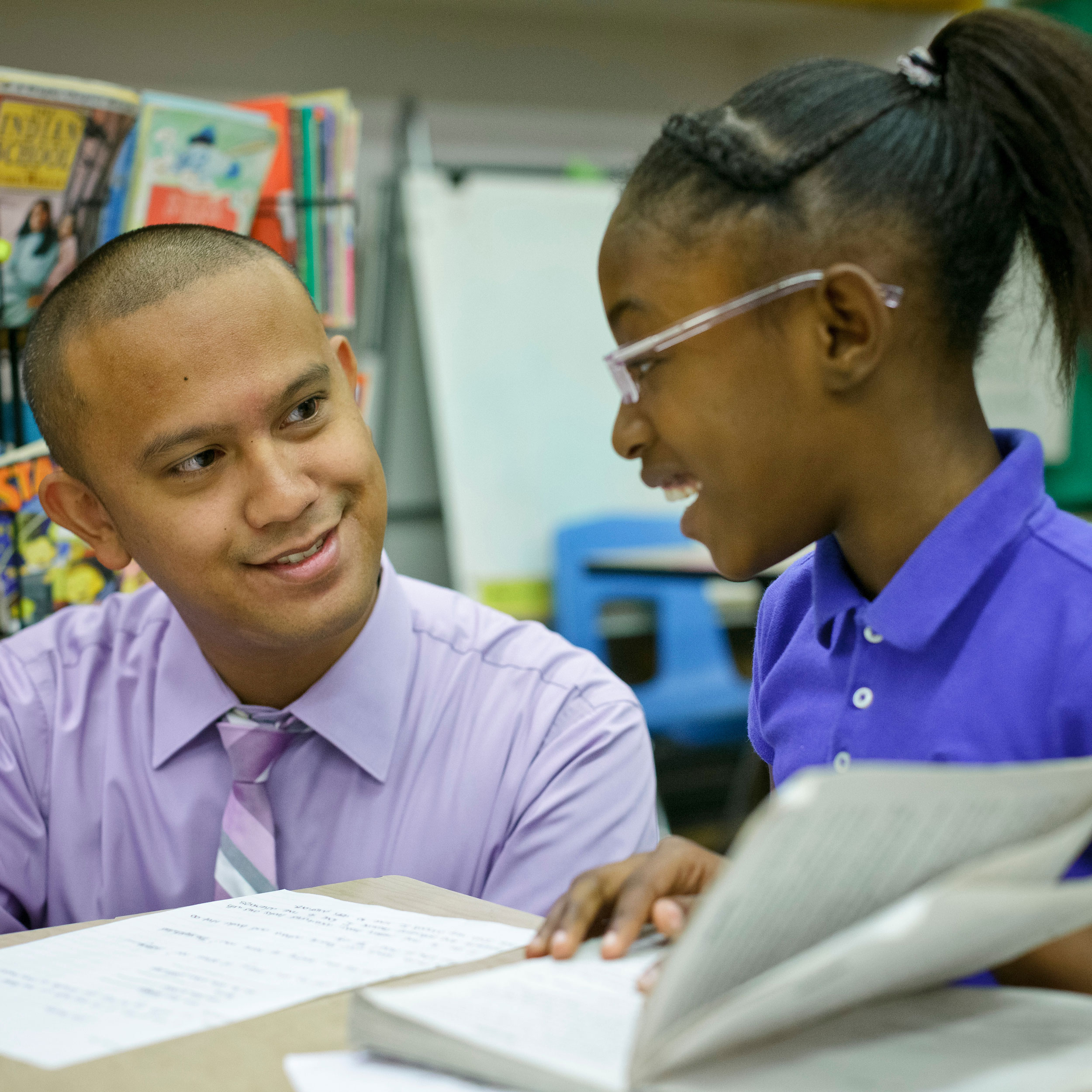 Teacher and student smiling and doing schoolwork