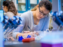 Photo of student writing observations while performing experiment.