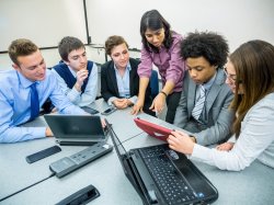 Business students and faculty looking at something on an Ipad