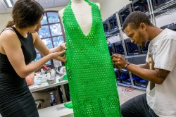 Photo of two students constructing a dress on a full-size manequin.