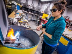 Photo of student using blowtorch to melt copper for sculpture.