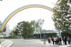 Photo of a group of people standing in front of a giant rainbow sculpture