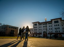 Photo of three students walking towards a building on campus