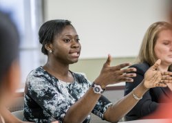 Photo of a young woman explaining a point in her class