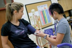 One student examining another with a stethoscope