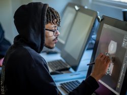 Illustration student wearing a hoodie and glasses drawing on a digital screen