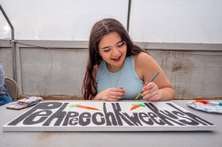 Student paints a garden sign with the Munsee language word for "carrot."