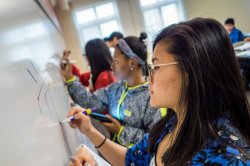 Students in Chinese class writing characters on a whiteboard