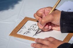 close-up of a hand holding a brush pen, writing in Hangul