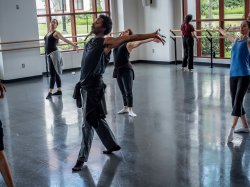 dancers in various poses in a studio with large windows